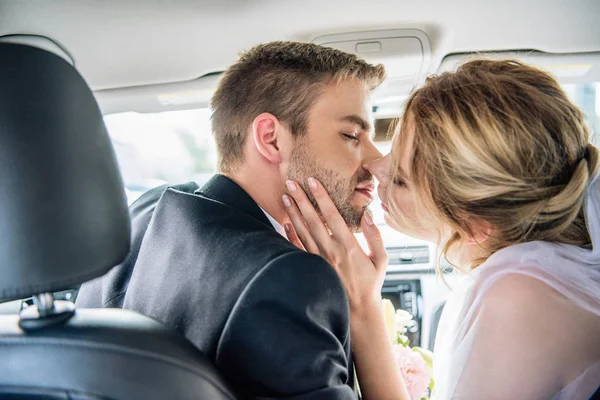 ブライダルベールと車の中でキス花婿の魅力的な花嫁のバックビュー — ストック写真