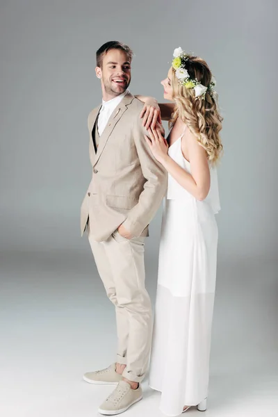 ウェディングドレスとスーツでハンサムな花婿を抱きしめる花輪の花嫁 — ストック写真