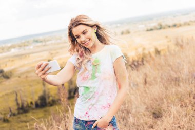 t-shirt çekici kadın gülümseyerek ve dışında selfie alarak 
