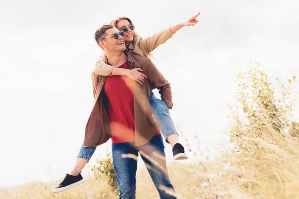 Stilig Man Piggybacking Hans Attraktiva Och Blonda Flickvän Utanför — Stockfoto