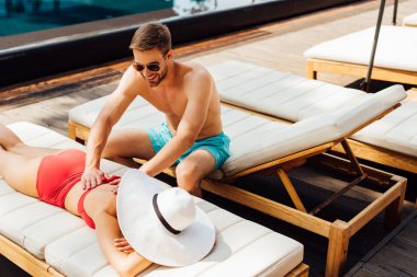 tatil de kız arkadaşı için masaj yapıyor güneş gözlüğü gülümseyen adam