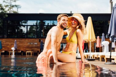 güneşli bir günde yüzme havuzunda kucaklayan seksi mutlu çift