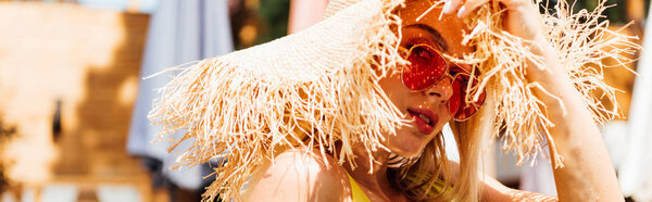 panoramic shot of attractive woman in sunglasses and straw hat