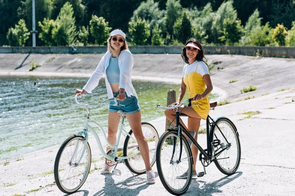 Chicas Rubias Morenas Felices Montando Bicicletas Cerca Del Río Verano —  Fotos de Stock