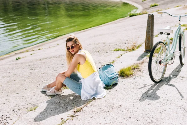 Blondine Pige Med Cykel Sidder Nær Floden Sommeren - Stock-foto