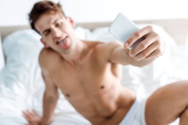 seksi ve gömleksiz adam yatak odasında selfie alarak seçici odak 
