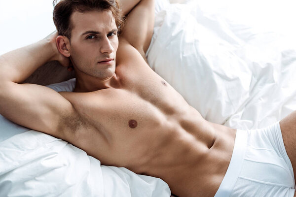 young sexy man lying on bed and looking at camera