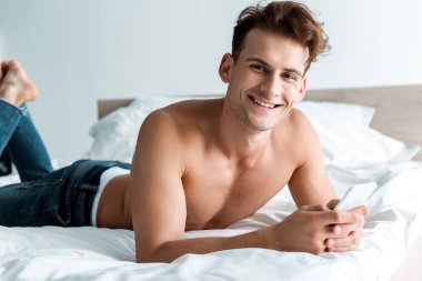 akıllı telefon kullanarak kot mutlu adam ve yatak odasında yalan 