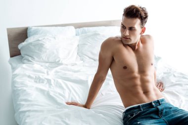 evde yatakta oturan kot pantolon seksi adam 