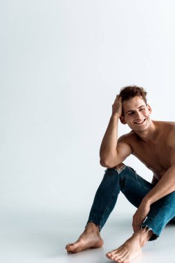 olumlu ve seksi adam saç dokunmadan ve beyaz oturuyor 