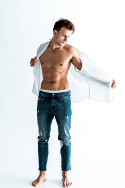 handsome man standing in blue jeans and undressing on white  clipart