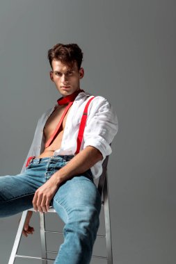 gri sandalyede oturan beyaz gömlekli seksi genç adam 