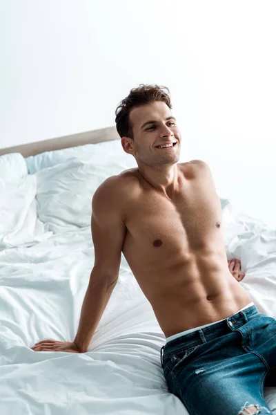Lycklig Ung Man Blå Jeans Sitter Sängen Hemma — Stockfoto