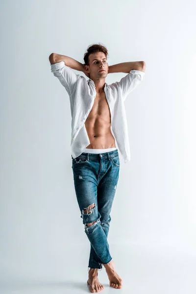 handsome young man in shirt and blue jeans standing on white