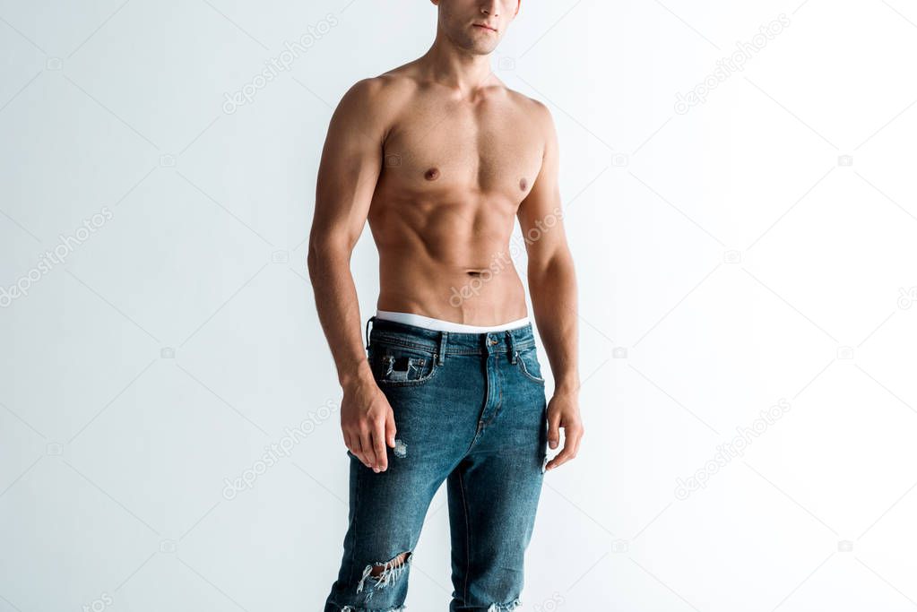 cropped view of shirtless man in jeans standing on white 