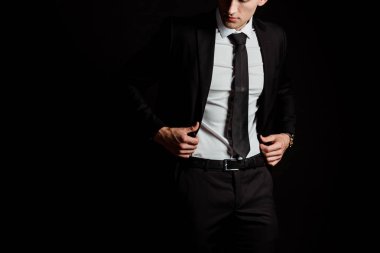 cropped view of man touching suit isolated on black  clipart
