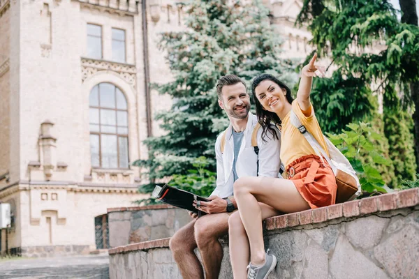 Mulher Feliz Apontando Com Dedo Sentado Perto Homem Com Mapa — Fotografia de Stock