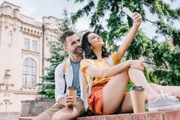 Szczęśliwa Kobieta Mówi Selfie Brodaty Mężczyzna Pobliżu Budynku — Zdjęcie stockowe