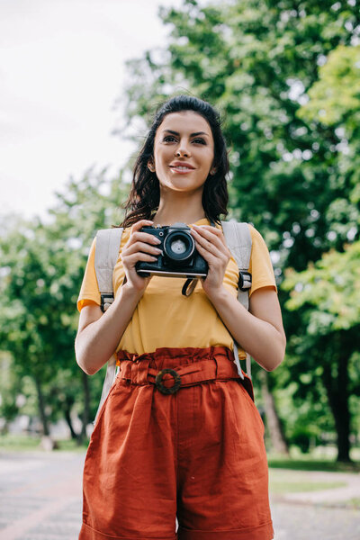 happy young woman holding digital camera outside 