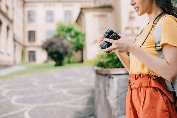 cropped view of girl holding digital camera near building 