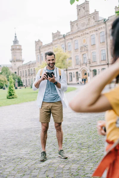 Selektywne Skupienie Szczęśliwy Człowiek Trzyma Aparat Cyfrowy Pobliżu Dziewczyny Kampusu — Zdjęcie stockowe