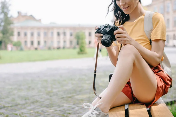 年轻女子坐在大学附近的长椅上 手持数码相机的剪影 — 图库照片