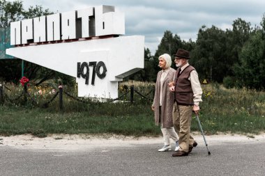 Pripyat, Ukrayna - 15 Ağustos 2019: emekli erkek ve kadın pripyat harflerle anıtın yakınında yürüyor