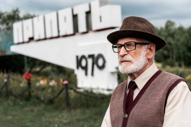 Pripyat, Ukrayna - 15 Ağustos 2019: pripyat harfleri ile anıt yakınında duran gözlük kıdemli sakallı adam