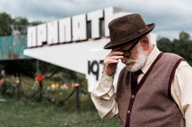 Pripyat, Ukrayna - 15 Ağustos 2019: pripyat harfleri ile anıt yakınında duran gözlük yaşlı adam üzgün