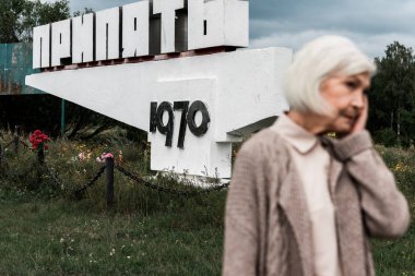 Pripyat, Ukrayna - 15 Ağustos 2019: Pripyat harfleri ile anıtın yanında duran emekli kadın