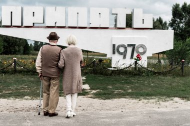 Pripyat, Ukrayna - 15 Ağustos 2019: pripyat harfleri ile anıt yakınında duran emekli çift in back view