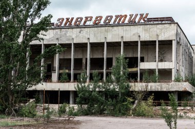 Pripyat, Ukrayna - 15 Ağustos 2019: Çernobil'de yeşil ağaçların yanında enerjik harflerle bina 