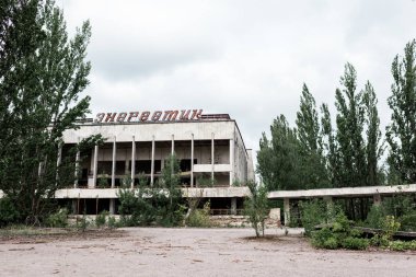 Pripyat, Ukrayna - 15 Ağustos 2019: Çernobil'de yeşil ağaçların yanında enerjik harflerle bina 