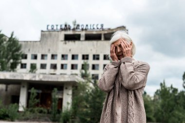Pripyat, Ukrayna - 15 Ağustos 2019: Çernobil'de otel polissya yazısı ile binanın yakınında yüz kapsayan kıdemli kadın 