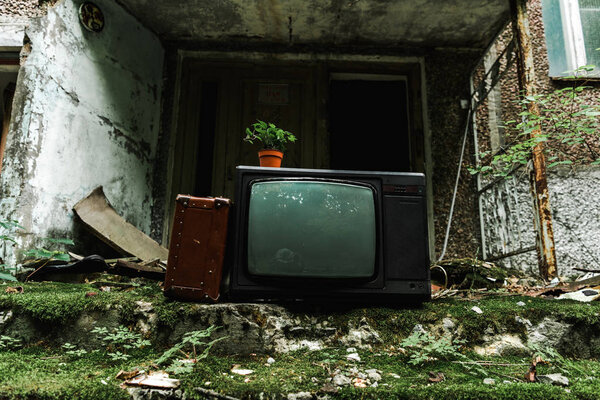 Ретро-телевизор рядом с дорожной сумкой на зеленой лестнице с плесенью
 