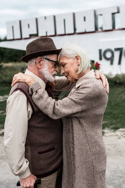 PRIPYAT, UKRAINE - AUGUST 15, 2019: selective focus of retired couple hugging near monument with pripyat letters 
