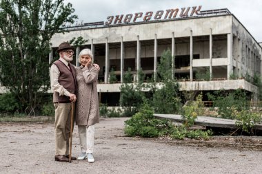 Pripyat, Ukrayna - 15 Ağustos 2019: Çernobil'de enerjik harflerle binanın yanında duran emekli çift 