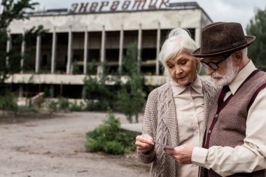 Pripyat, Ukrayna - 15 Ağustos 2019: üst düzey çift çernobil enerjik yazı ile binanın yakınında fotoğraf bakıyor 