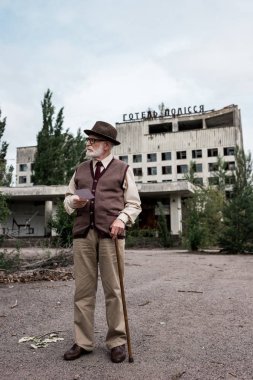 Pripyat, Ukrayna - 15 Ağustos 2019: otel polissya mektupları ile binanın yakınında fotoğraf tutan baston yürüyen kıdemli adam