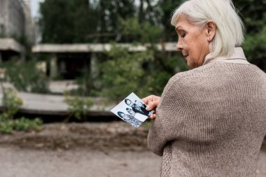 Pripyat, Ukrayna - 15 Ağustos 2019: siyah beyaz fotoğrafa bakan gri saçlı yaşlı kadın