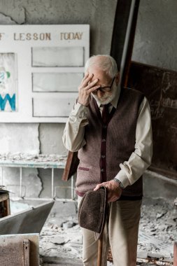 mektuplar ile kurulu yakınında dururken şapka tutan üzgün üst düzey adam 