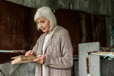 Pripyat, Ukrayna - 15 Ağustos 2019: elinde kitap tutan gri saçlı kıdemli kadın