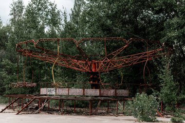 Pripyat, Ukrayna - 15 Ağustos 2019: Çernobil'deki yeşil eğlence parkında terk edilmiş kırmızı metalik atlıkarınca 