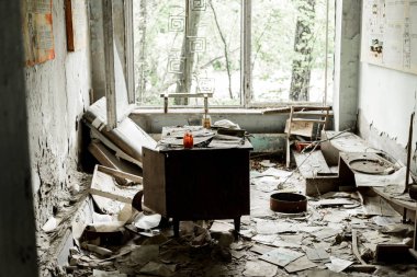 PRIPYAT, UKRAINE - AUGUST 15, 2019: abandoned and damaged room with papers and documents on floor  clipart