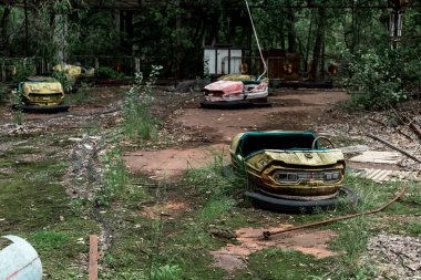 PRIPYAT, UKRAINE - AUGUST 15, 2019: selective focus of abandoned bumper cars in amusement park 