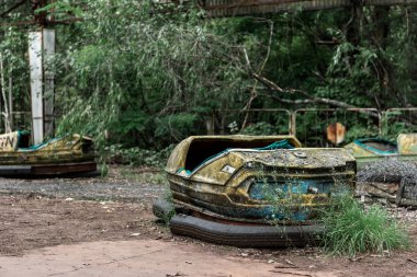 PRIPYAT, UKRAINE - AUGUST 15, 2019: selective focus of abandoned and dirty bumper cars in amusement park  clipart