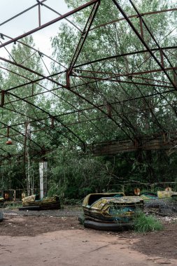 PRIPYAT, UKRAINE - AUGUST 15, 2019: dirty and abandoned bumper cars in amusement park  clipart