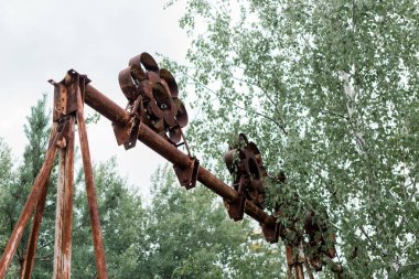 Pripyat, Ukrayna - 15 Ağustos 2019: Parkta metalik yapıya yakın ağaçların düşük açılı görünümü 