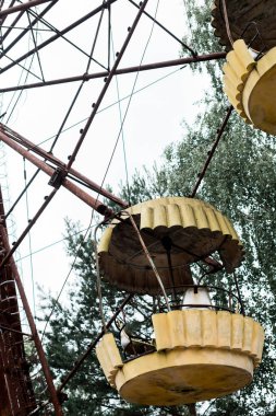 PRIPYAT, UKRAINE - AUGUST 15, 2019: metallic ferris wheel in green amusement park in chernobyl  clipart