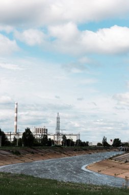 PRIPYAT, UKRAINE - AUGUST 15, 2019: abandoned chernobyl nuclear power plant near trees and river  clipart
